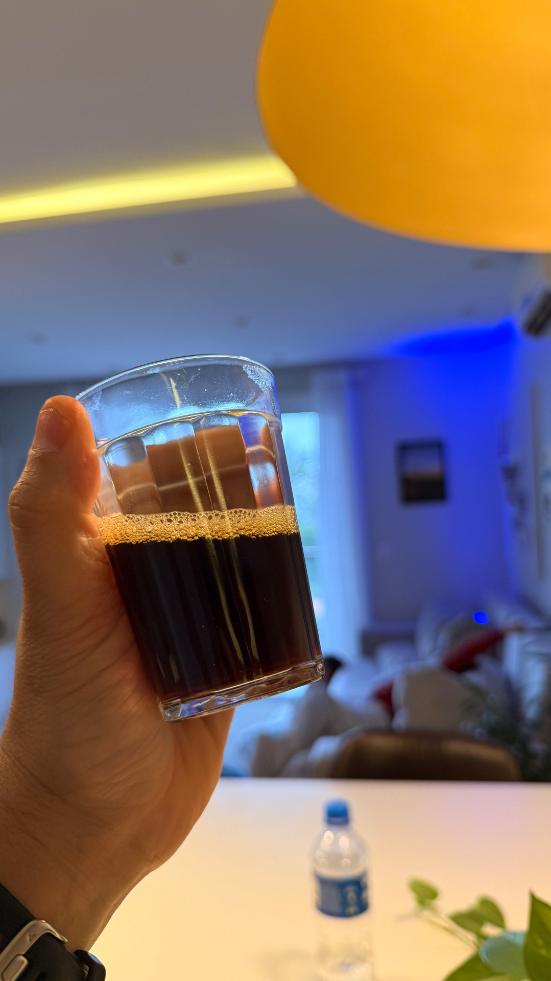 Café preto à mão sob luz quente de uma luminária amarela